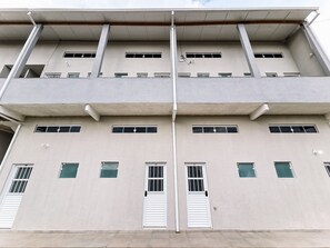 Un edifici de diversos pisos amb façana plana, nombroses finestres i un element estructural vertical central.