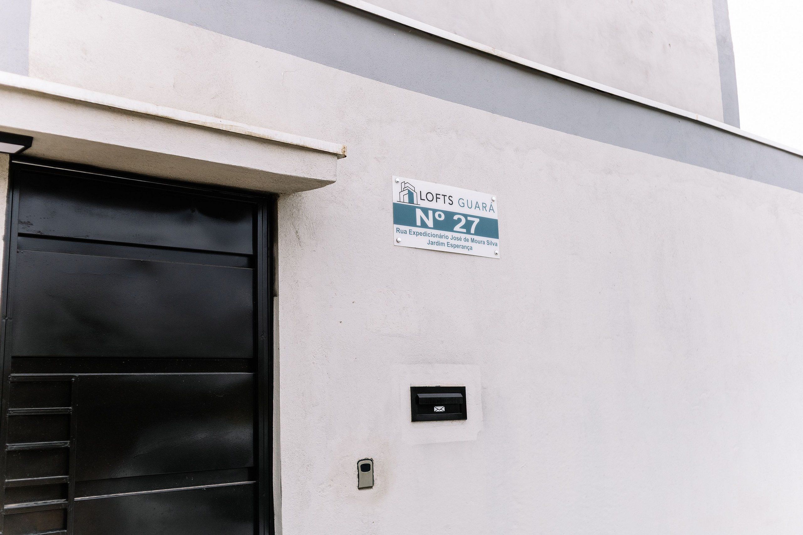 Un edificio con un letrero que indica 'LOFTS GUARÁ No 27 Rua Expedicionário José de Moura Silva Jardim Esperança'.