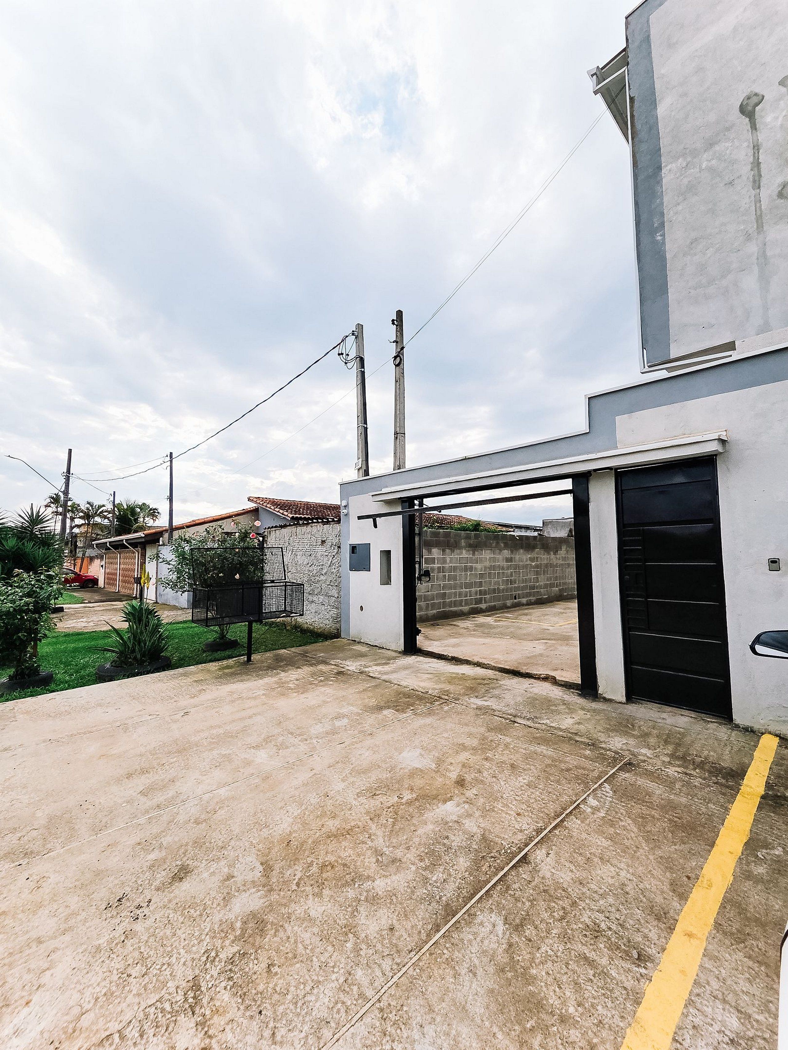 A parking area with a gated entrance, a concrete ground, and a building with a garage door.