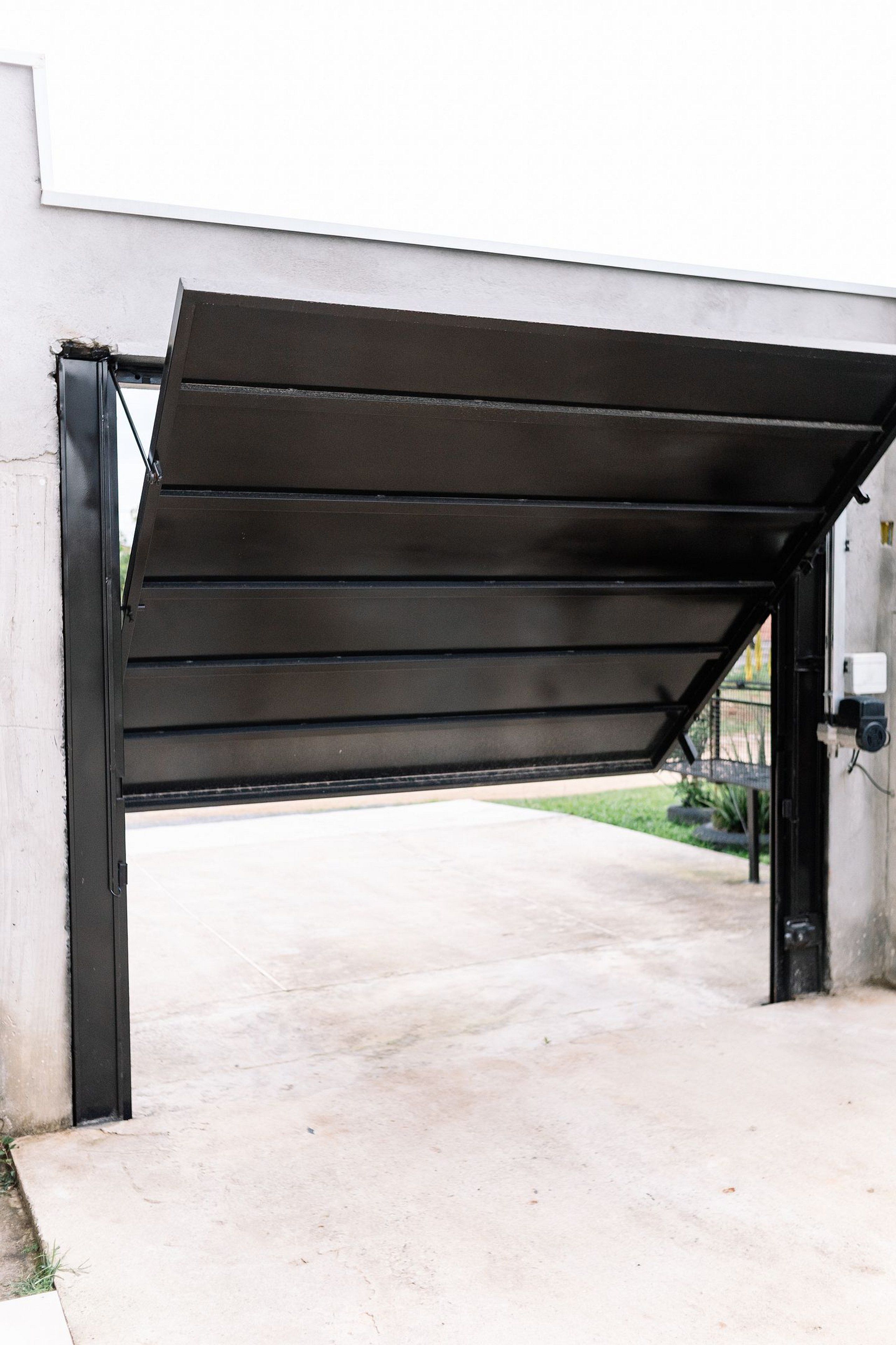 Un garaje con una puerta de metal negro y suelo de hormigón.