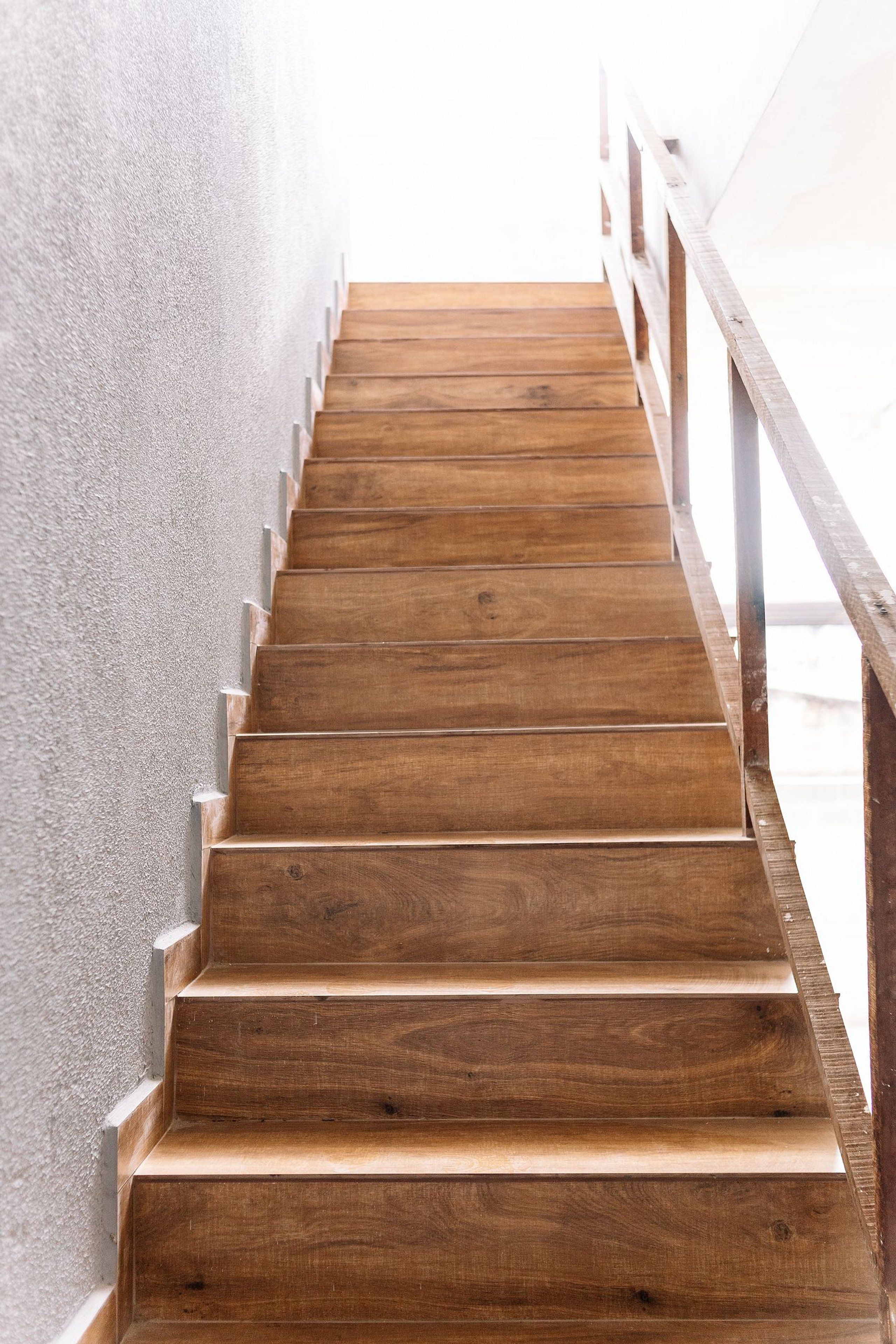 A wooden staircase with a metal railing, leading upwards.