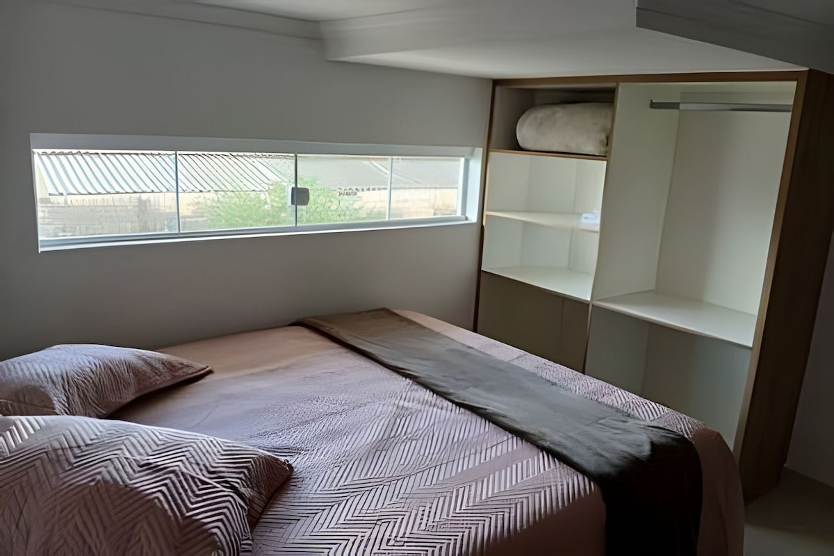 A bedroom with a bed, a window, and a built-in wardrobe.