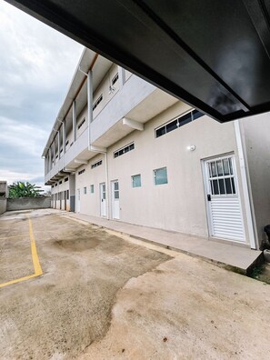 A multi-story building with a flat facade, multiple windows, and a gated entrance.