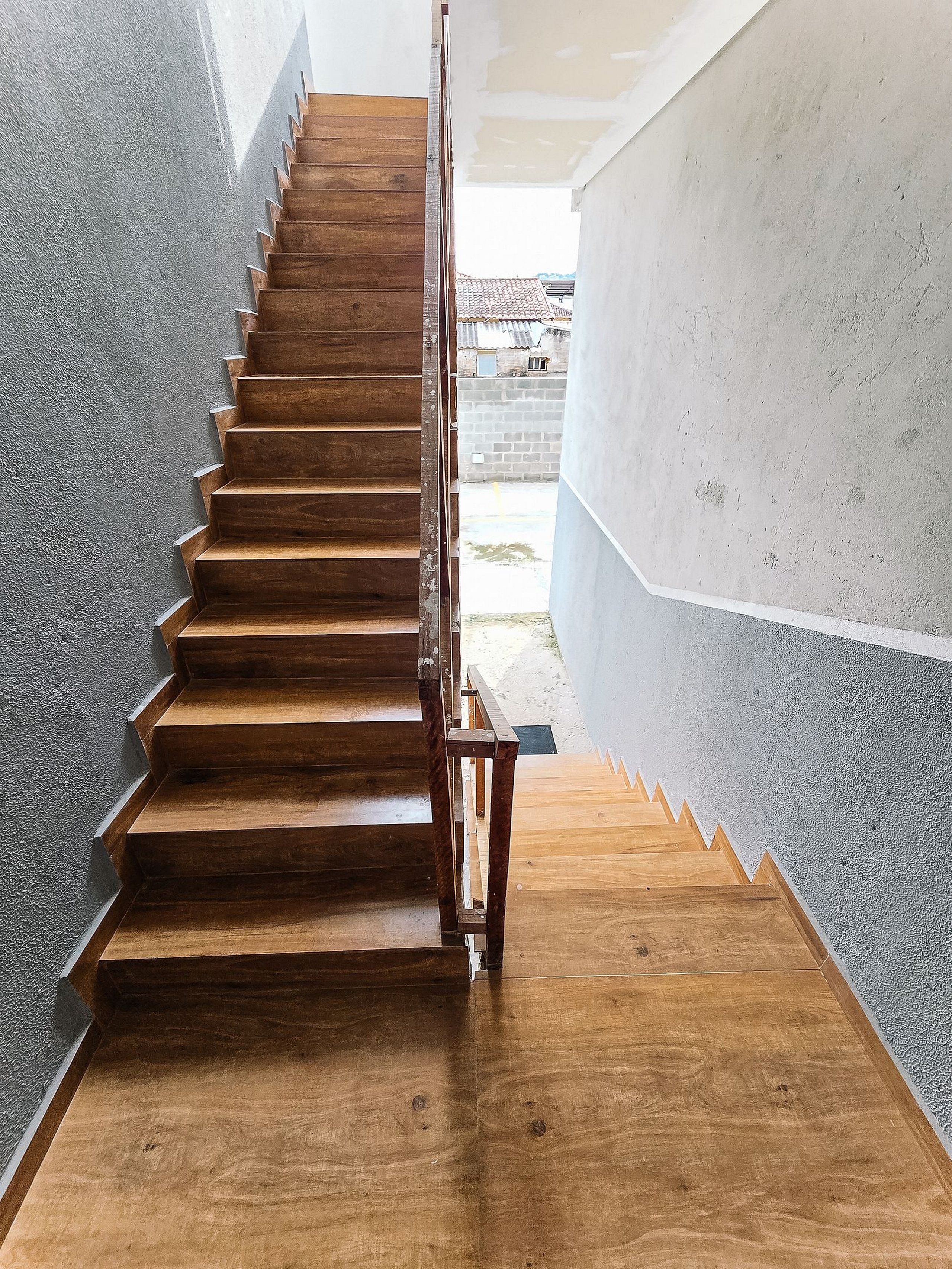 A wooden staircase with a metal railing leading to an outdoor area.