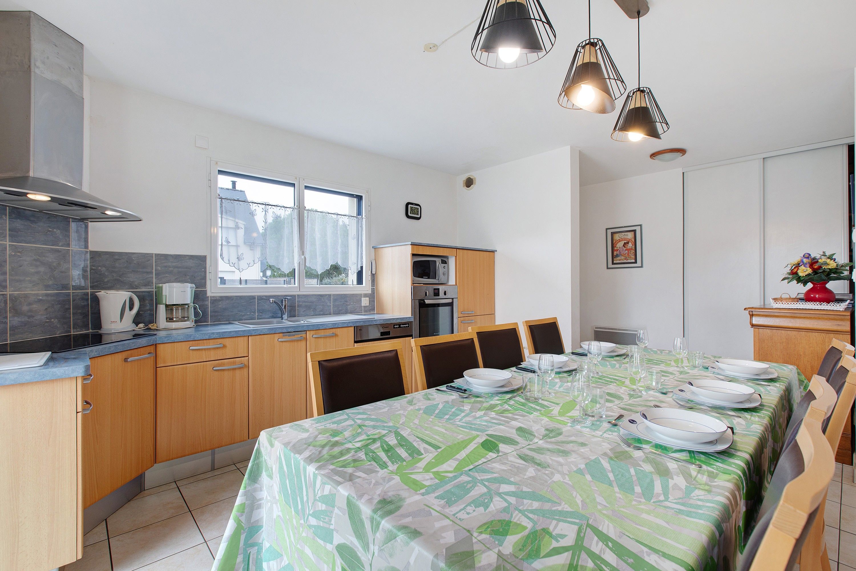 A modern kitchen with a dining area, featuring a kitchen island, wooden cabinets, and a dining table set for four.