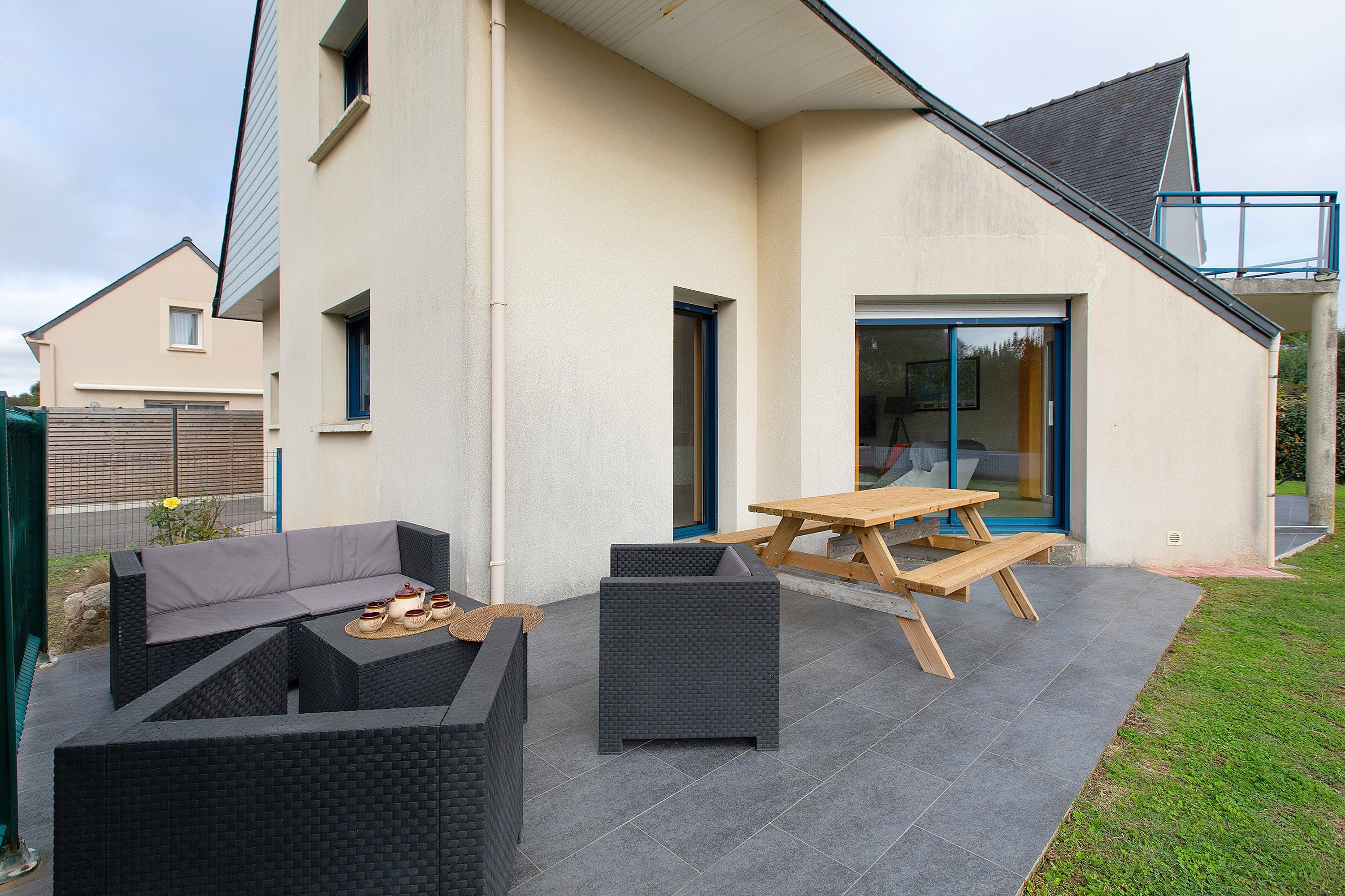 A patio with outdoor furniture, a wooden table, and a black wicker sofa.