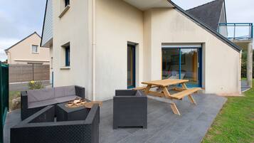 A patio with outdoor furniture, a wooden table, and a black wicker sofa.