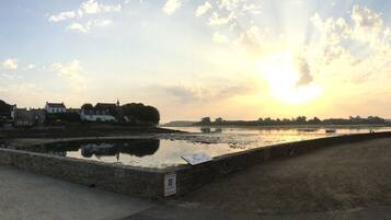 Blick auf das Wasser mit einer Steinmauer, einem Schild und Gebäuden im Hintergrund.