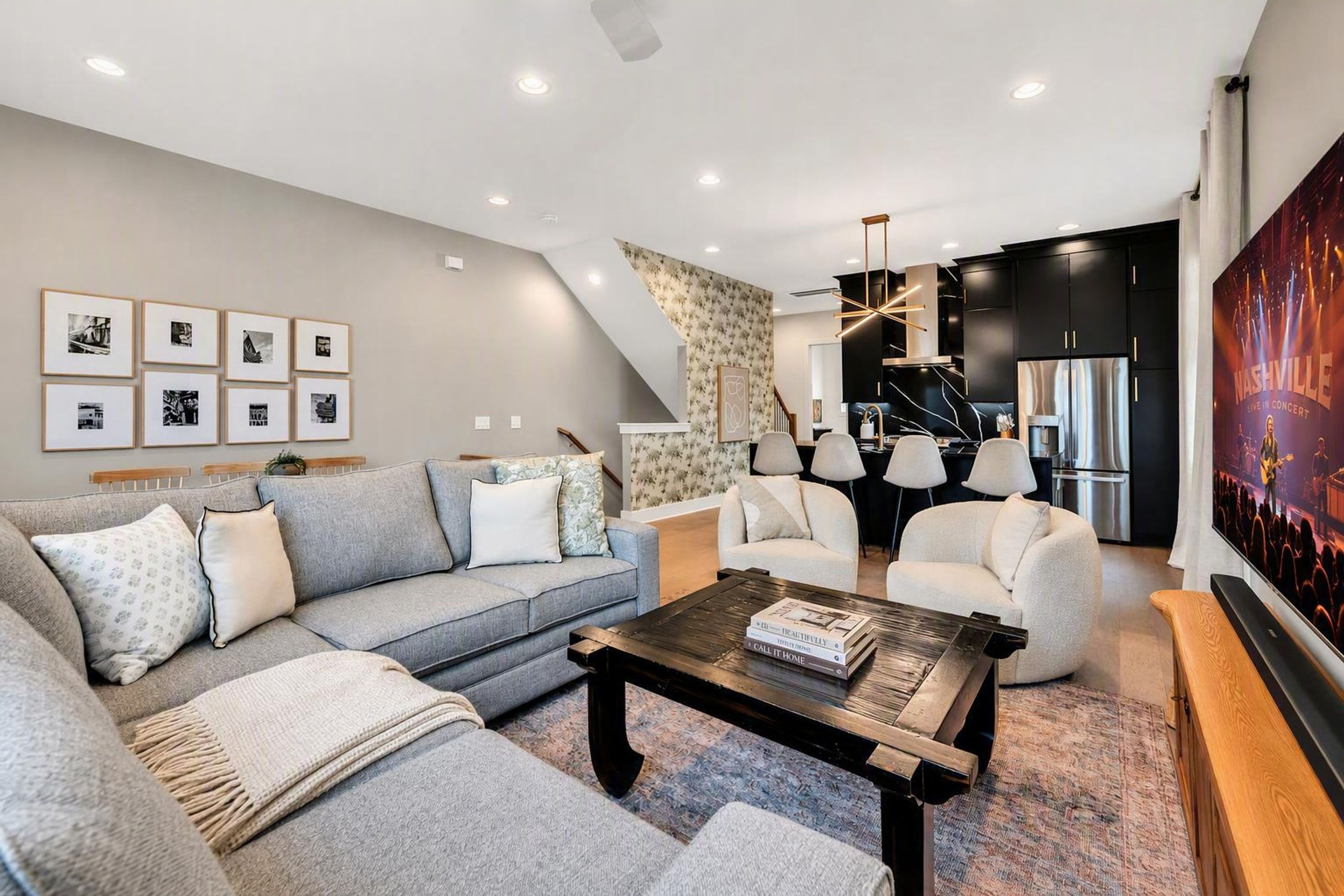 A modern living room with a grey sofa, a coffee table, and a TV screen displaying a concert.