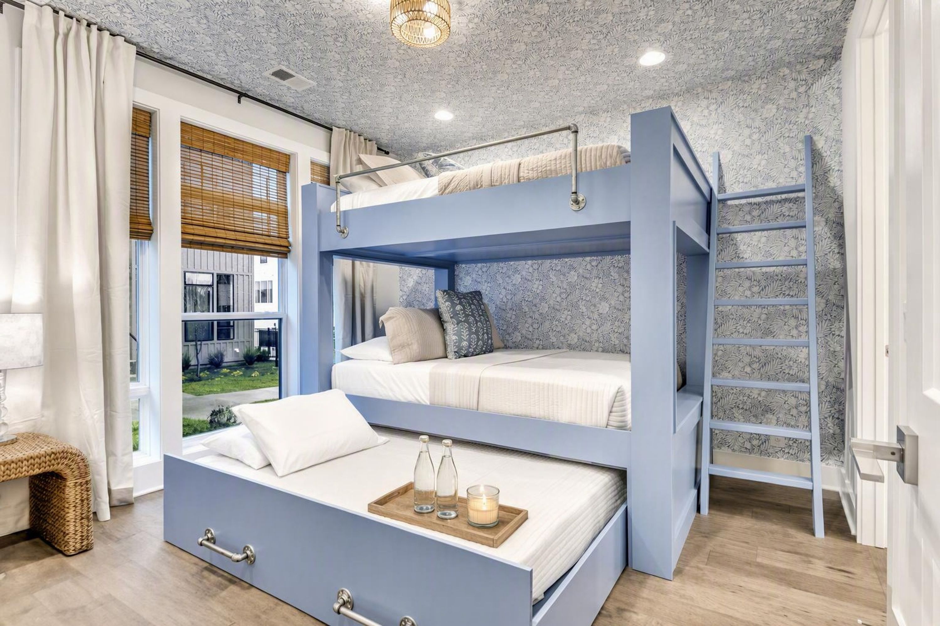 A bunk bed room with a view of a garden and a wooden floor.