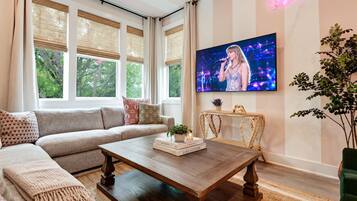 A modern living room with a sofa, coffee table, and a TV displaying a performer.