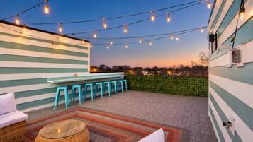 An outdoor patio with a bar area, seating, and string lights.