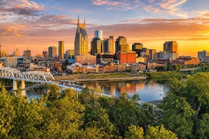 A city skyline with modern buildings, a river, and a bridge. - 2 Homes - Rooftop Decks - Fire Pit - Sleeps 24 (Nashville)