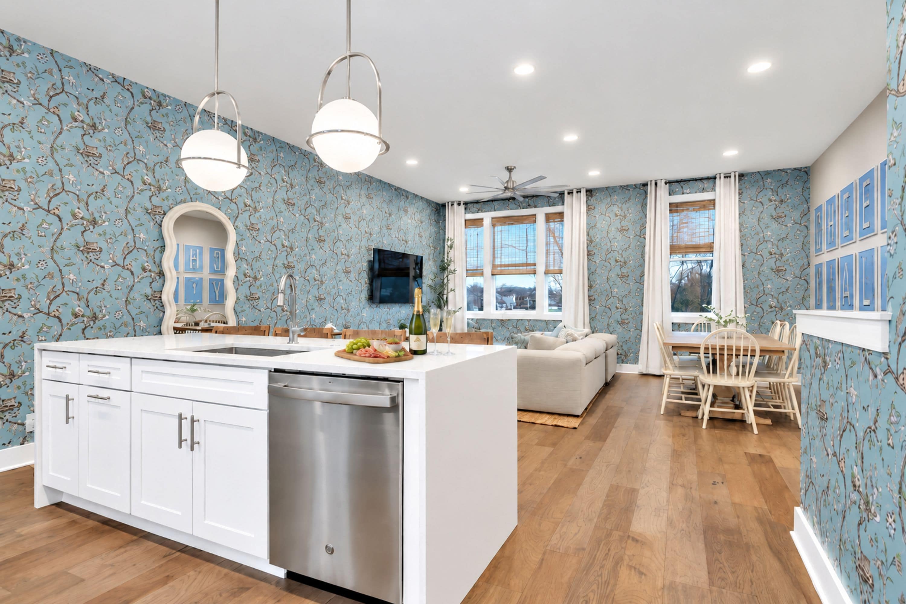 A modern kitchen with white cabinetry, a dishwasher, and a dining area with a wooden table and chairs.