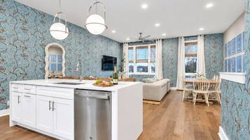 A modern kitchen with white cabinetry, a dishwasher, and a dining area with a wooden table and chairs.