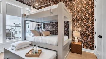 Een moderne slaapkamer met een stapelbed, een nachtkastje met een lamp, en uitzicht op de stad door grote ramen.