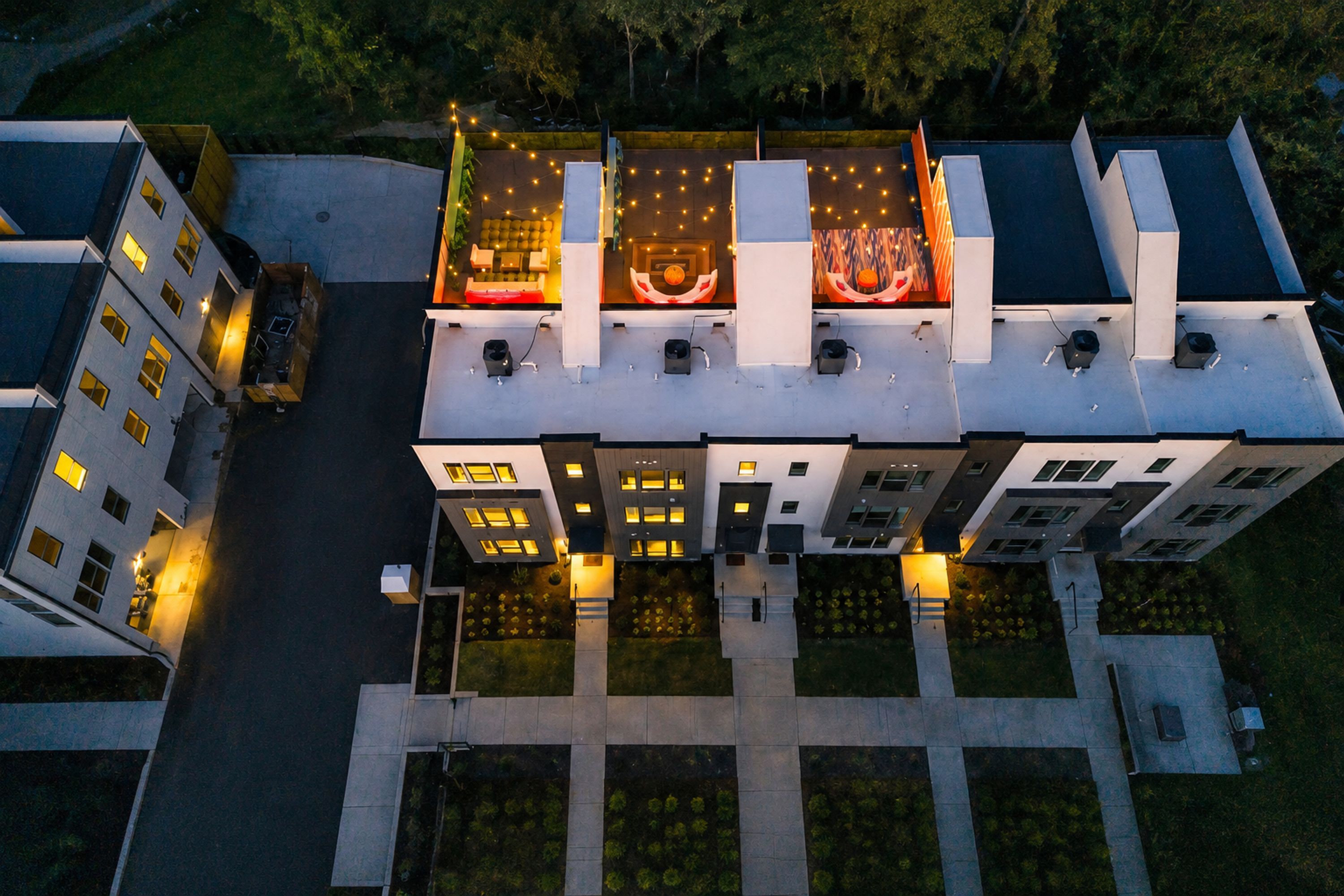 A multi-story building with a central courtyard, multiple balconies, and a rooftop terrace with string lights.