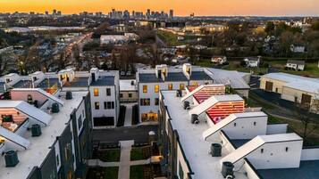 A modern apartment complex with multiple buildings, rooftop terraces, and a city skyline in the background.