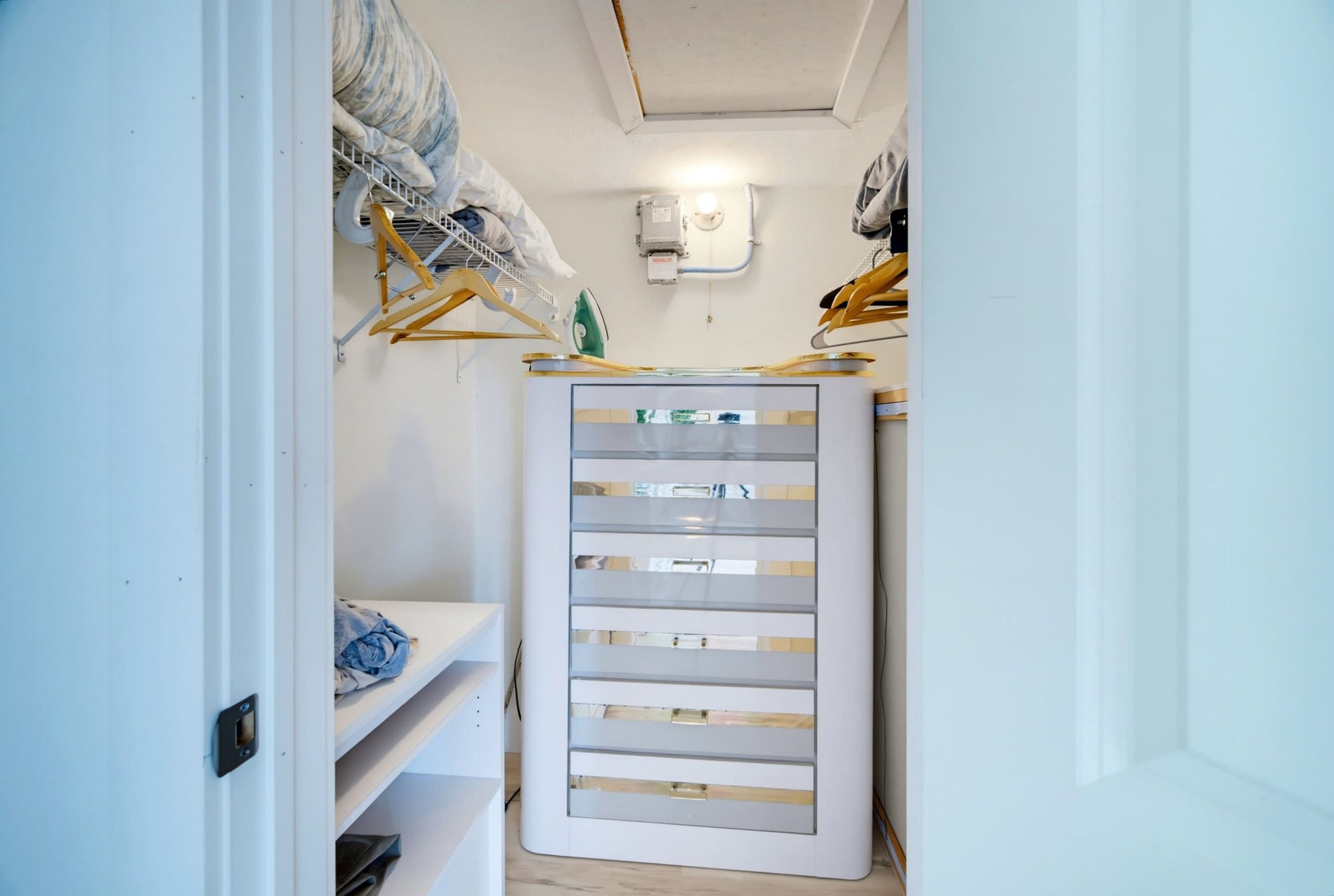 A narrow hallway with a white storage unit featuring multiple drawers and shelves.