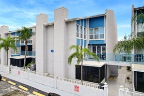 Un immeuble moderne à plusieurs étages, doté de balcons, d’un espace de stationnement et surplombant un ciel dégagé.