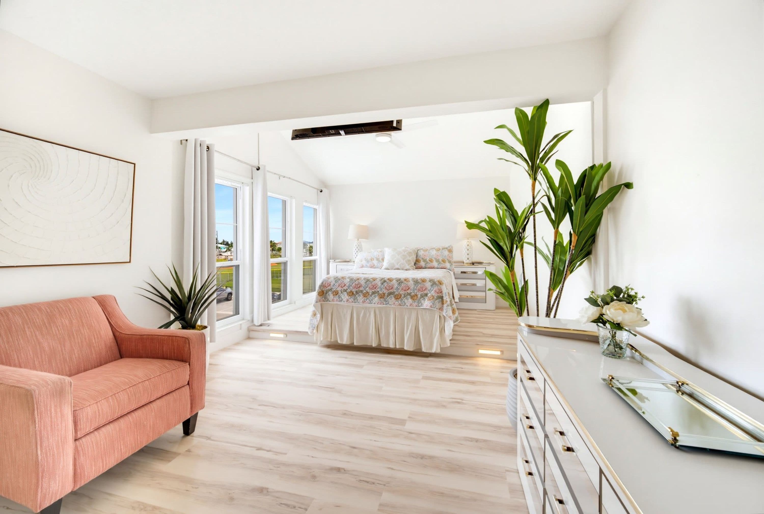 A spacious bedroom with a large bed, a sitting area with a sofa, and a view of the outdoors through a sliding door.