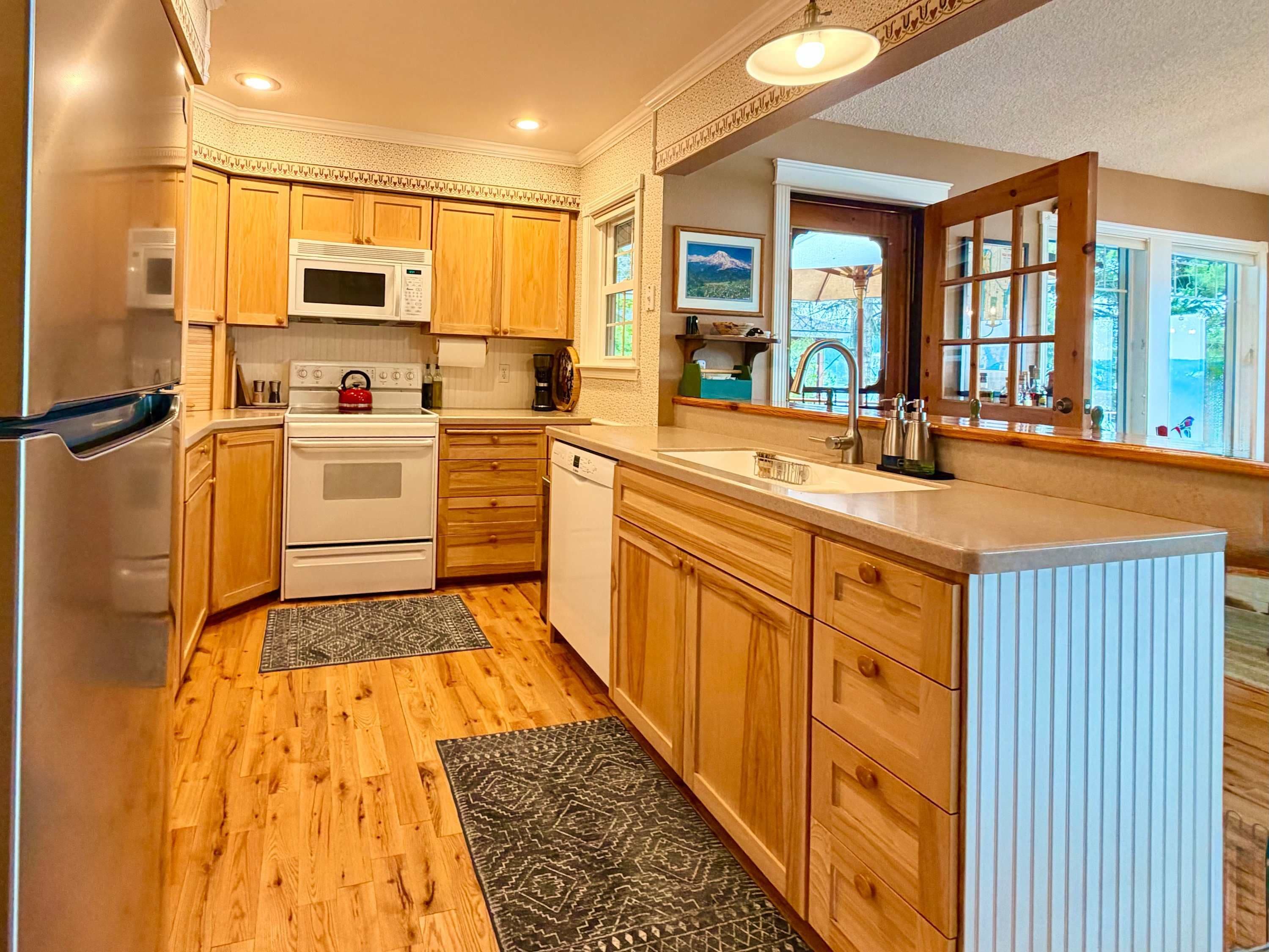 A compact kitchen with wooden cabinets, a microwave, stove, and a sink.
