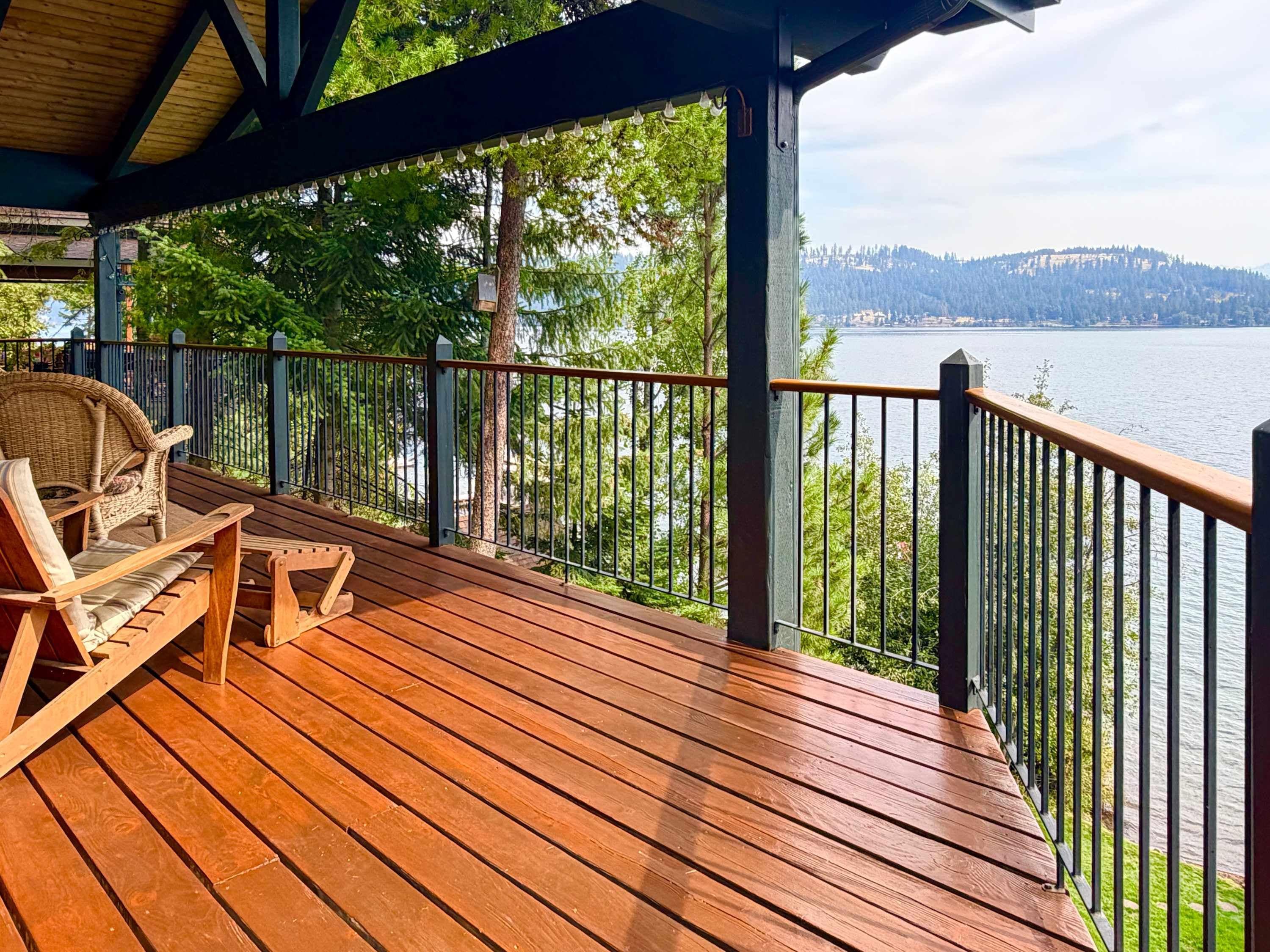A wooden deck with a view of a lake and forest.