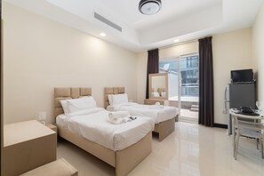 A hotel room with two beds, a TV, a small table, and a window with curtains. - Stayshort - Spacious 11-bedroom Villa Stay at Casa Royale JVC (Dubai)