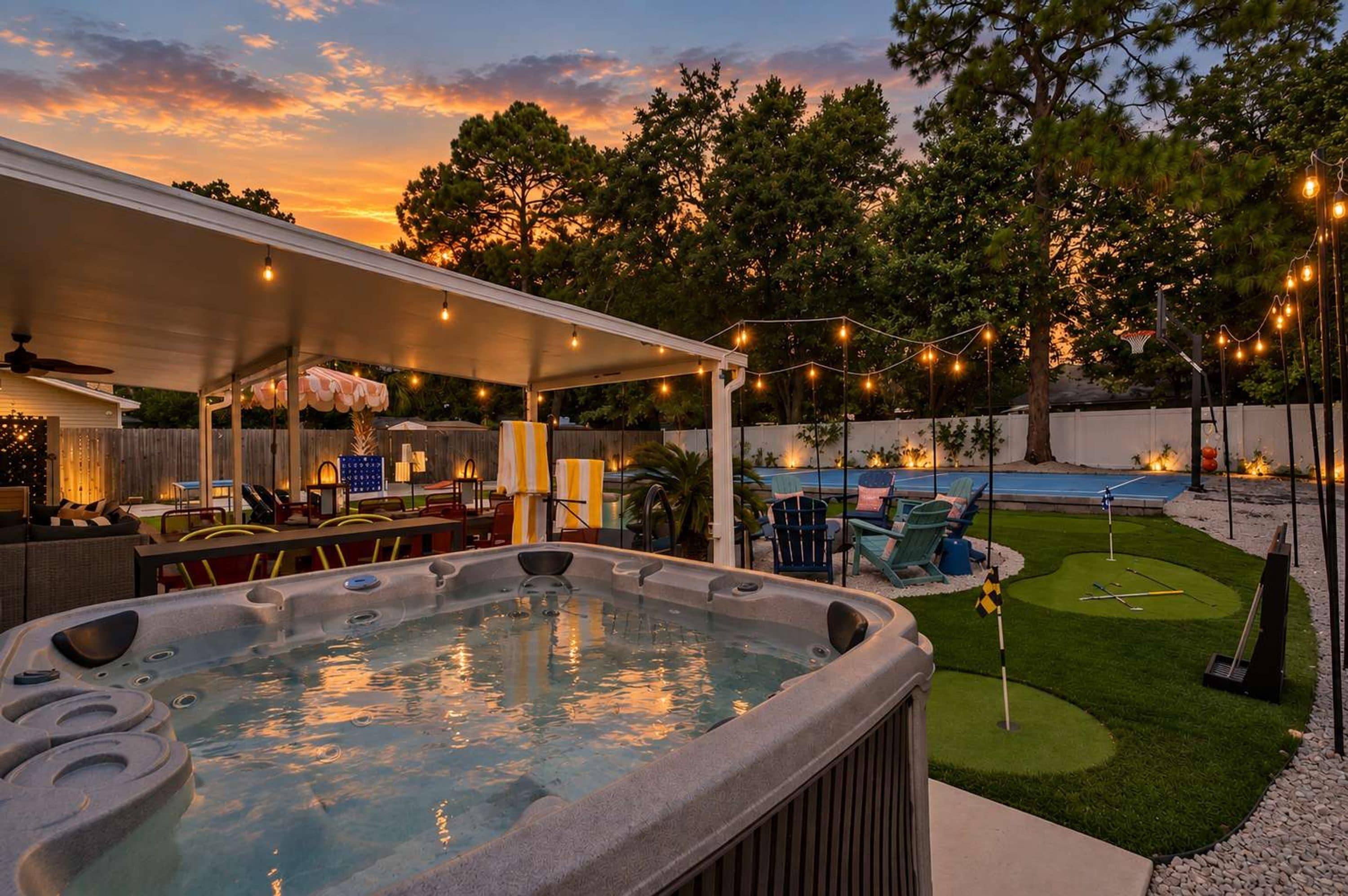 A backyard with a hot tub, outdoor seating, and a pool.