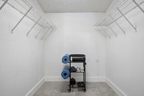 A storage closet with metal shelving units and a black cart for luggage. - FWB Paradise Sports Court Hot Tub Putt Putt (Fort Walton Beach)