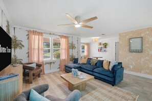 A living room with a sofa, armchairs, a coffee table, and a ceiling fan. - FWB Paradise Sports Court Hot Tub Putt Putt (Fort Walton Beach)