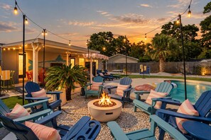 Ein Außenbereich mit Terrassenmöbeln, einem Feuerkorb, Liegestühlen und einem Pool.