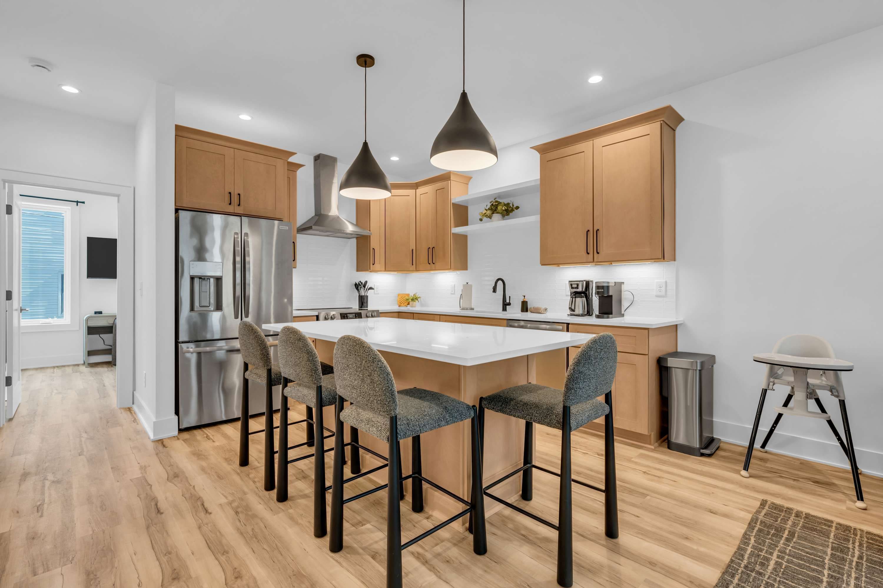 Una cocina moderna con electrodomésticos de acero inoxidable, armarios de madera y una isla central con taburetes de bar.