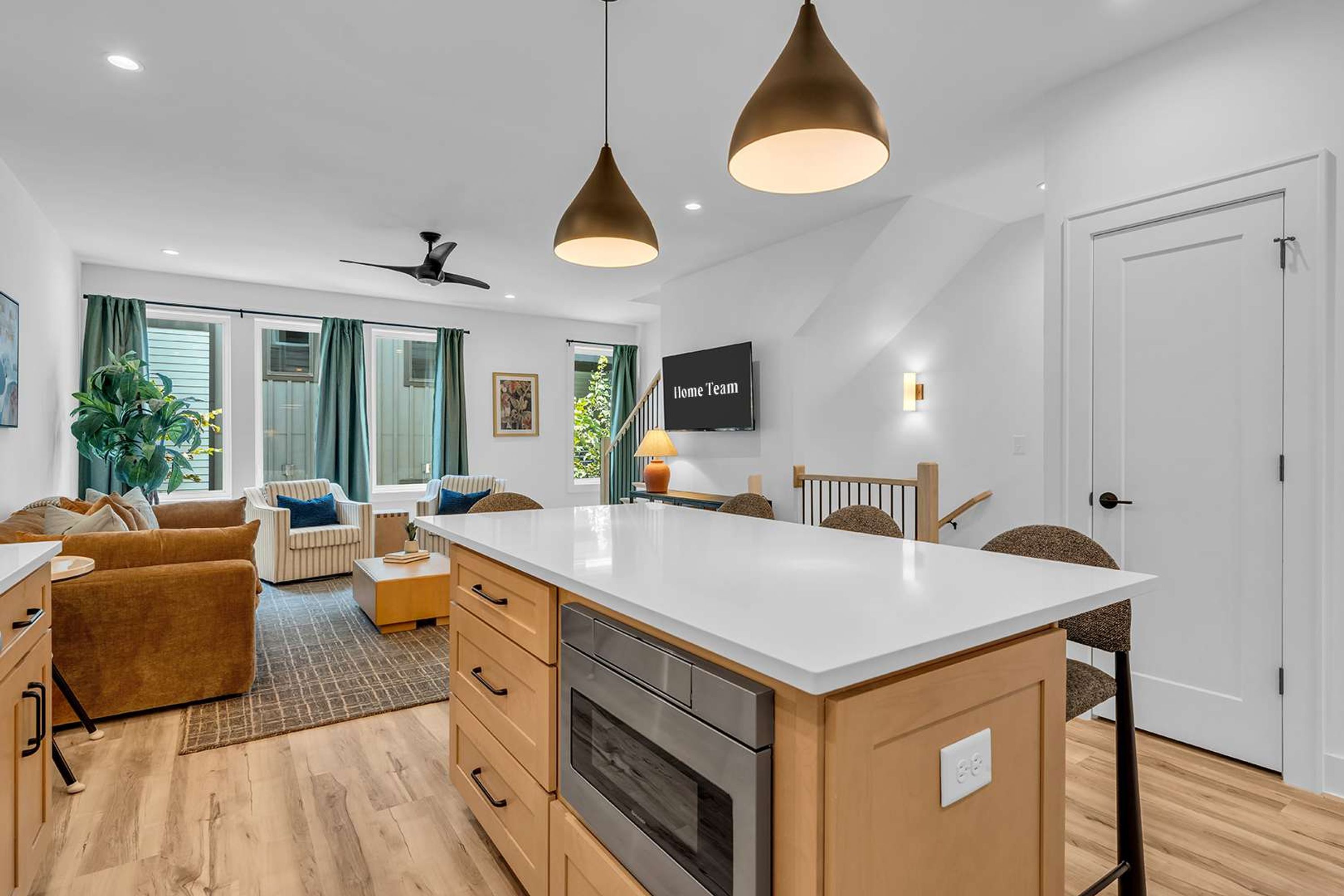 A modern kitchen with a central island, wooden cabinets, and a built-in oven.