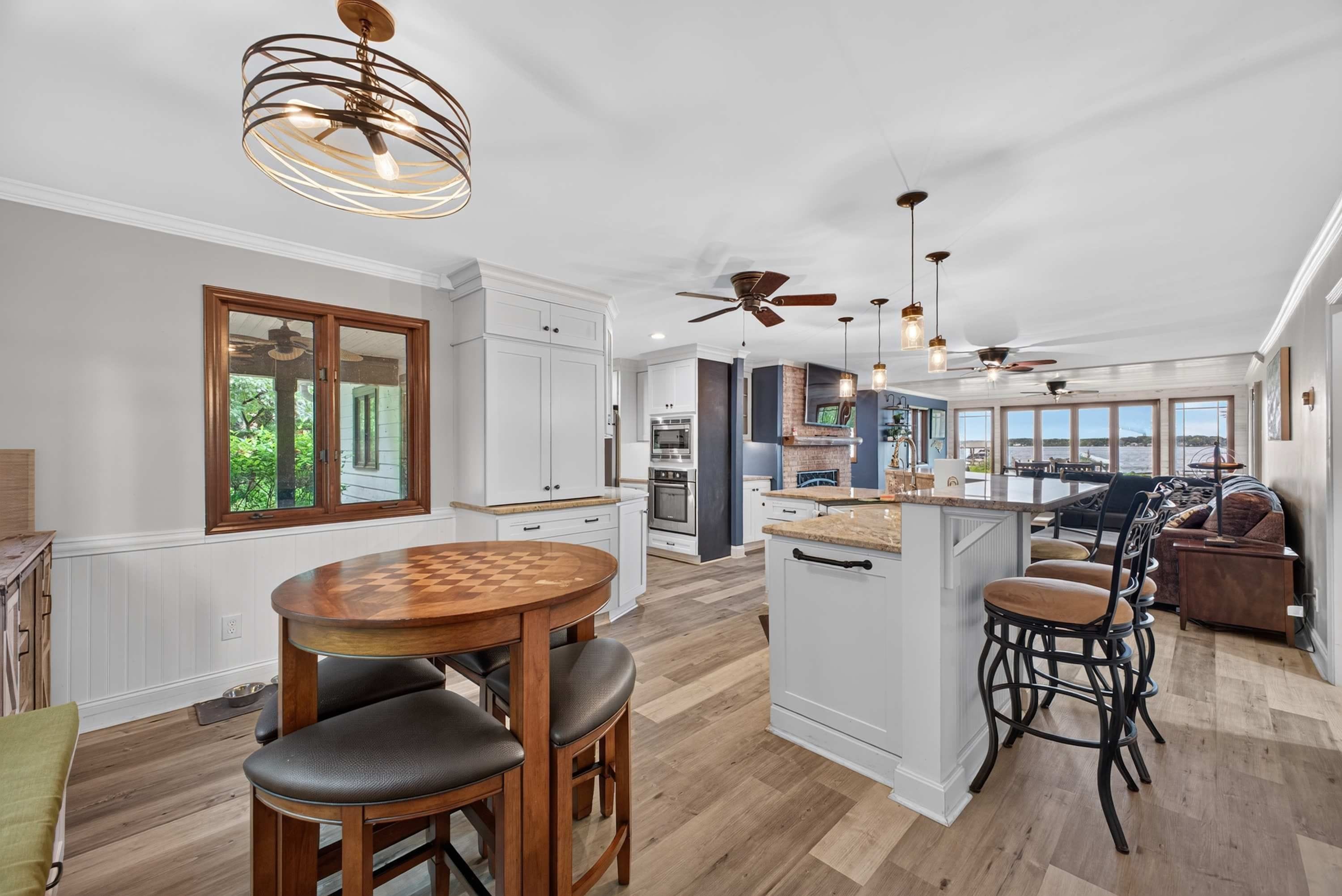 A spacious kitchen with a central island, a dining area with a wooden table, and a seating area with chairs.