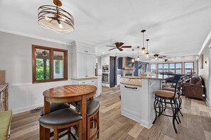 A spacious kitchen with a central island, a dining area with a wooden table, and a seating area with chairs. - Lake Norman Haven Private Dock Lake Views (Denver)
