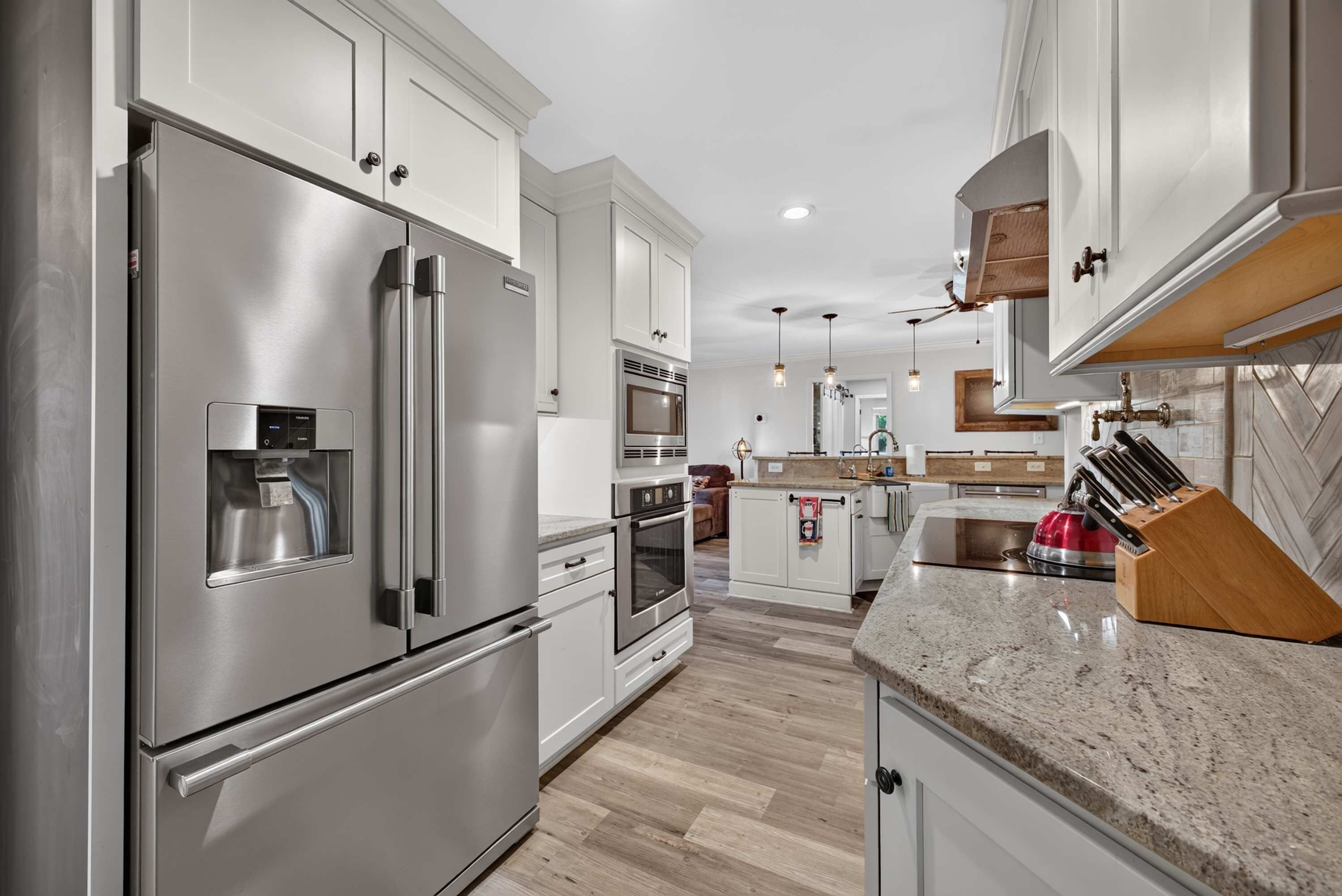 A modern kitchen with stainless steel appliances, a granite countertop, and wooden cabinetry.
