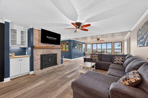 A modern living room with a fireplace, a television mounted on the wall, and a large window offering a view of the outdoors. - Lake Norman Haven Private Dock Lake Views (Denver)