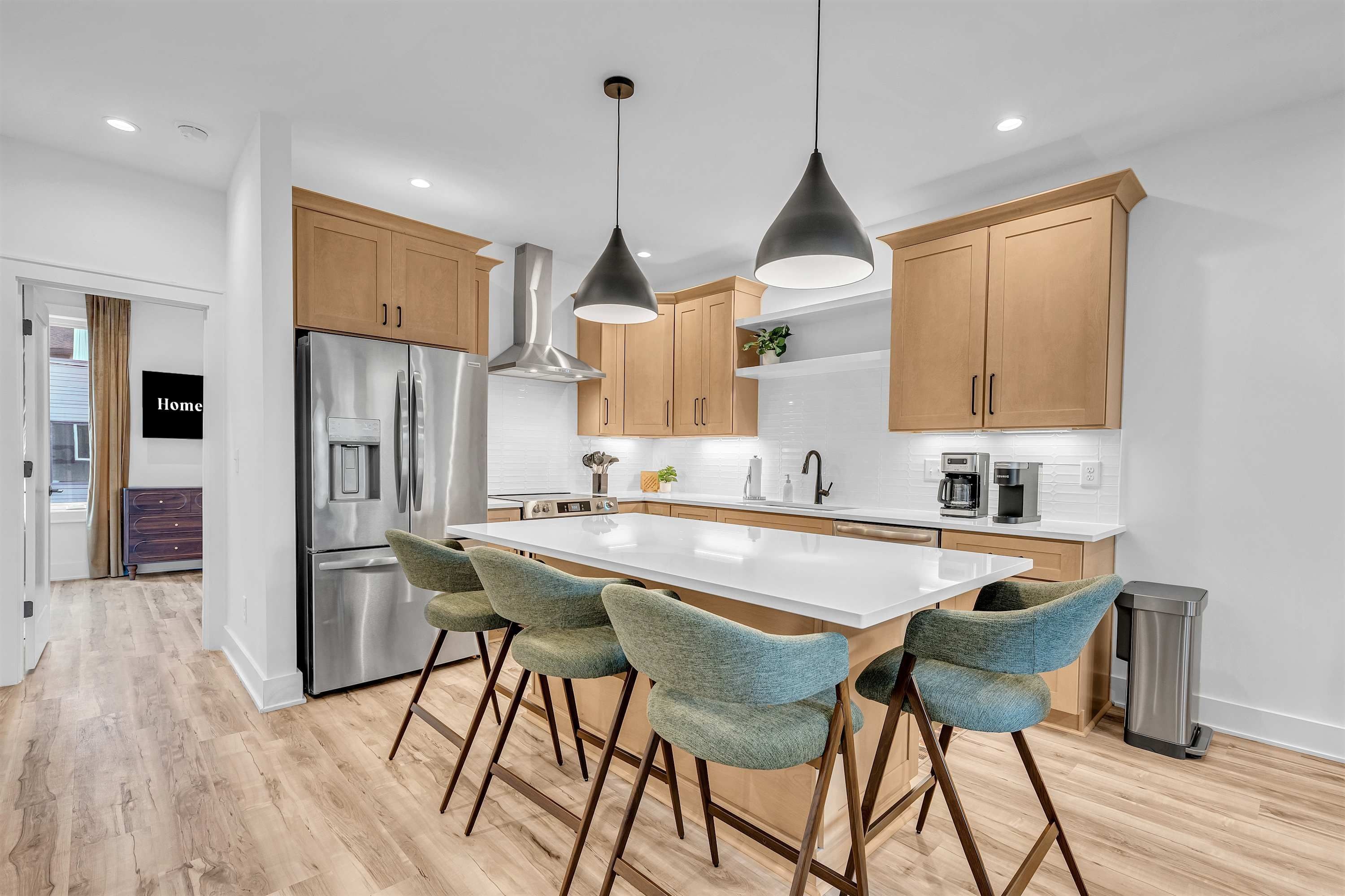 A modern kitchen with stainless steel appliances, wooden cabinets, and a central island with bar stools.