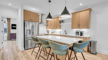 A modern kitchen with stainless steel appliances, wooden cabinets, and a central island with bar stools.