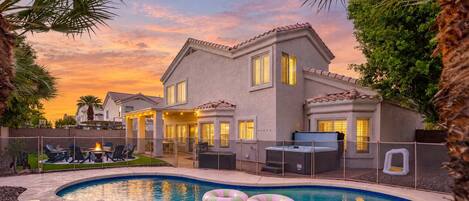 A residential property with a swimming pool, outdoor seating, and a patio area.