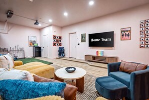 A modern living room with a flat-screen TV, comfortable seating, and a small table. - Adobe Afterglow Swim Soak Play Stay Awhile (Mesa)