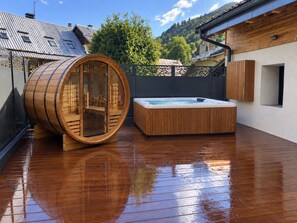 A wooden sauna with a barrel-shaped design, a hot tub, and a wooden deck. - Chalet 'Le Manoir Valloire Ski' (Valloire)