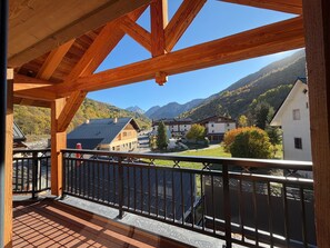 Un balcone in legno con vista su un villaggio montano e case.
