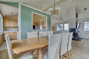 A dining area with a wooden table and chairs, a kitchen with wooden cabinets, and a fireplace. - Serene 3BR Waterfront Home Balcony With Bay Views (Point Roberts)