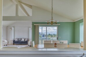 Un salón amplio con un ventanal grande, una zona de comedor con sillas y un sofá.