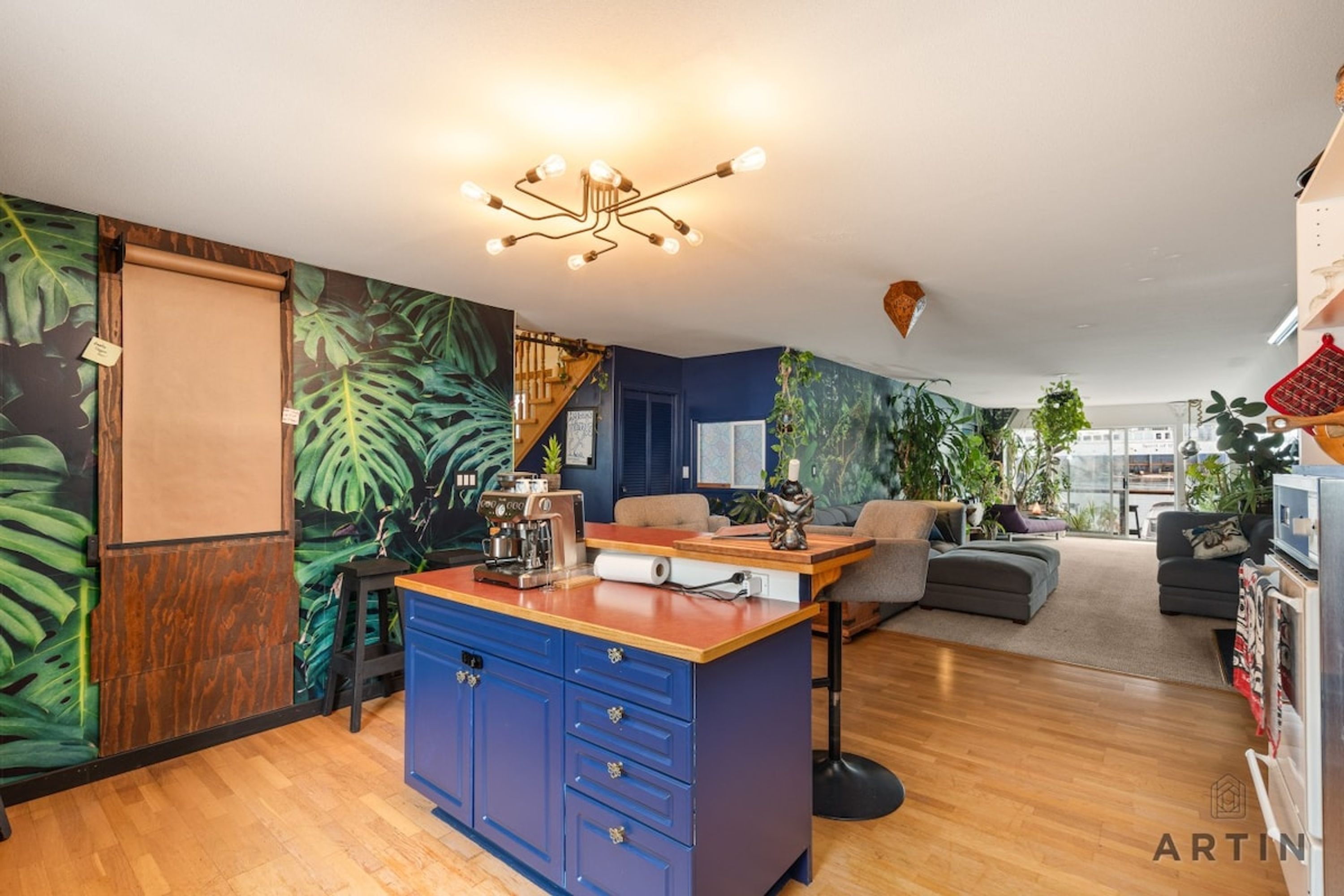 A modern living space with a kitchen island, a coffee machine, and a dining area.
