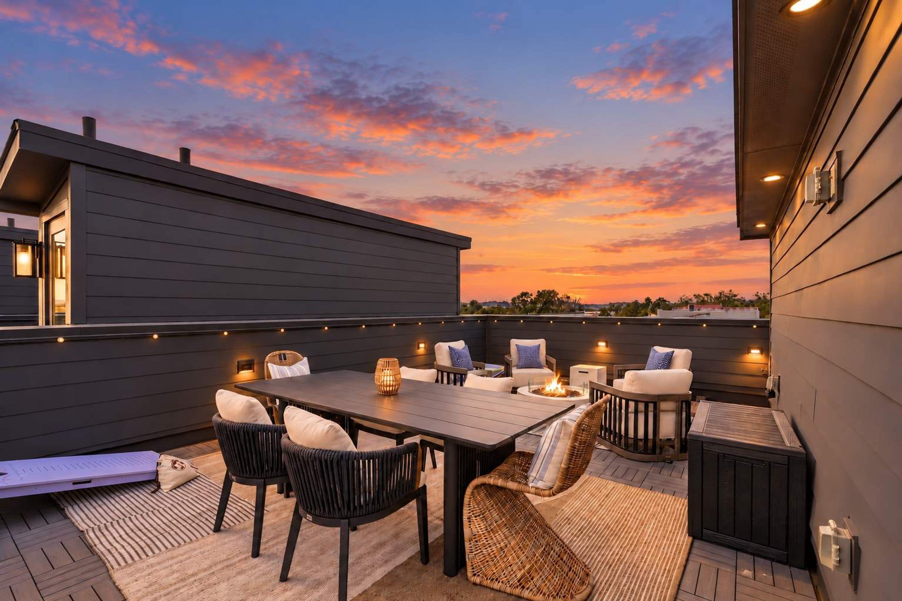 Un patio al aire libre con una mesa y sillas de comedor, rodeado de luces colgantes.