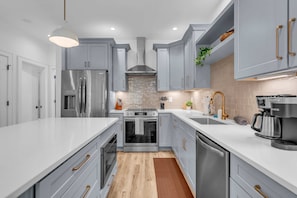 Una cocina moderna con electrodomésticos de acero inoxidable, armarios grises y una isla central.