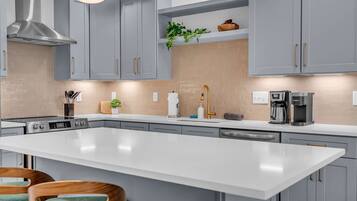 A modern kitchen with grey cabinets, a large island, and stainless steel appliances.